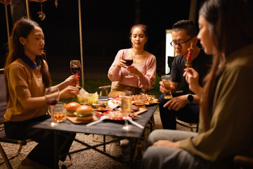 Happy Friends Celebrating Together at Night, Young Asian Group of Friends Having Fun and Toasting Drinks Outdoors, Enjoying a Celebration Concept.