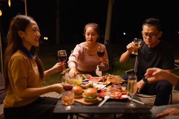 Happy Friends Celebrating Together at Night, Young Asian Group of Friends Having Fun and Toasting Drinks Outdoors, Enjoying a Celebration Concept.