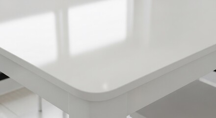 Obraz premium Close-up of a modern white table with a glossy, reflective surface and a softly rounded corner.