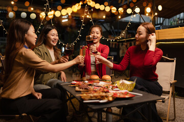 Happy Group of Woman Friends Celebrating Together at Night, Сlinking glasses of dinner at a social gathering.
