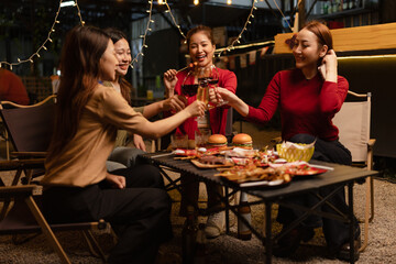 Happy Group of Woman Friends Celebrating Together at Night, Сlinking glasses of dinner at a social gathering.