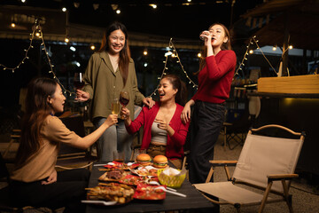 Happy Group of Woman Friends Celebrating Together at Night, Сlinking glasses of dinner at a social gathering.