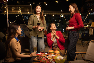 Happy Group of Woman Friends Celebrating Together at Night, Сlinking glasses of dinner at a social gathering.