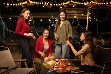 Happy Group of Woman Friends Celebrating Together at Night, Сlinking glasses of dinner at a social gathering.