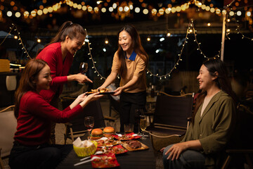 Happy Group of Woman Friends Celebrating Together at Night, Сlinking glasses of dinner at a social gathering.
