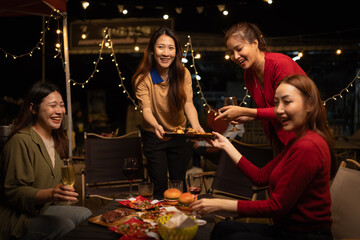 Happy Group of Woman Friends Celebrating Together at Night, Сlinking glasses of dinner at a social gathering.