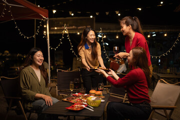 Happy Group of Woman Friends Celebrating Together at Night, Сlinking glasses of dinner at a social gathering.