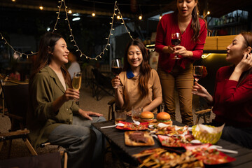 Happy Group of Woman Friends Celebrating Together at Night, Сlinking glasses of dinner at a social gathering.