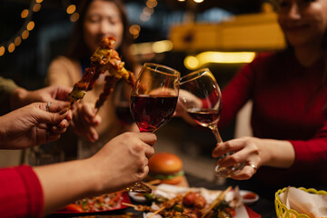 Happy Group of Woman Friends Celebrating Together at Night, Сlinking glasses of dinner at a social gathering.