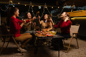 Happy Group of Woman Friends Celebrating Together at Night, Сlinking glasses of dinner at a social gathering.