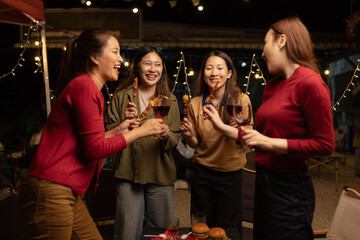 Fototapeta premium Happy Group of Woman Friends Celebrating Together at Night, Сlinking glasses of dinner at a social gathering.