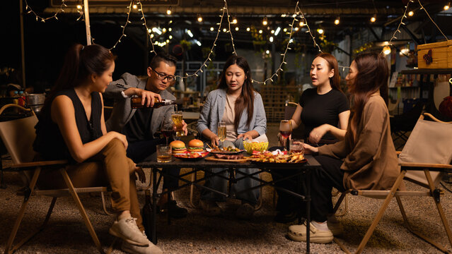 Happy Friends Celebrating Together at Night, Young Asian Group of Friends Having Fun and Toasting Drinks Outdoors At Night, Enjoying a Celebration Concept. - Powered by Adobe