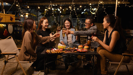 Happy Friends Celebrating Together at Night, Young Asian Group of Friends Having Fun and Toasting Drinks Outdoors At Night, Enjoying a Celebration Concept.
