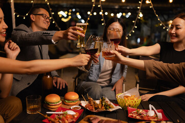 Happy Friends Celebrating Together at Night, Young Asian Group of Friends Having Fun and Toasting Drinks Outdoors At Night, Enjoying a Celebration Concept.