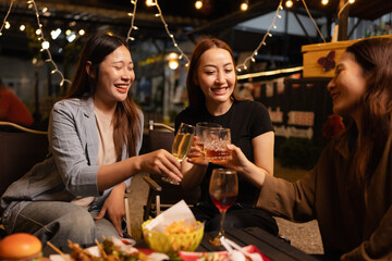Happy Friends Celebrating Together at Night, Young Asian Group of Friends Having Fun and Toasting Drinks Outdoors At Night, Enjoying a Celebration Concept.