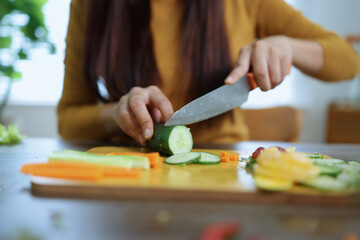 Obraz premium Happy young woman preparing healthy food in the kitchen.