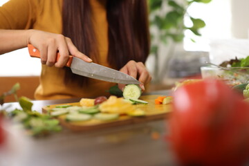 Happy young woman preparing healthy food in the kitchen.