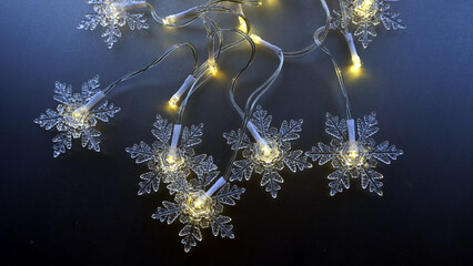 A string of Christmas lights shaped like snowflakes. Dark blue background. Christmas festive...