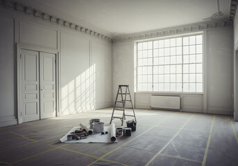 A room under renovation with tools and blueprints on the floor near a ladder