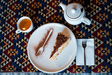 Cake Slice with Tea on Patterned Tablecloth