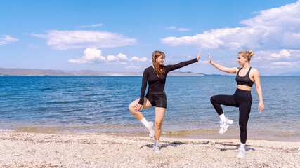Friends practicing yoga poses on the beach by the lake on a sunny day