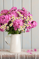Phlox and chamomile bouquet in white ceramic pitcher