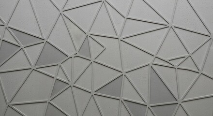 A textured gray surface is adorned with an intricate geometric pattern of interconnected raised lines forming numerous triangles Subtle tonal variations add depth to the abstract design