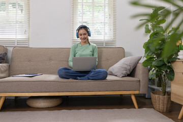 Woman reading a book with blue headphones and a laptop at home, Relaxation & Leisure Learn online...