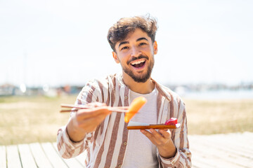 Handsome Arab man at outdoors holding sashimi