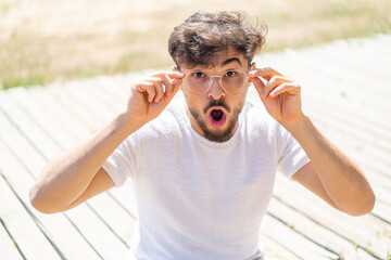 Handsome Arab man at outdoors With glasses and surprised expression