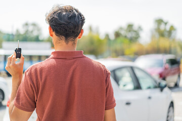 Young Arabian handsome man holding car key at outdoors in back position