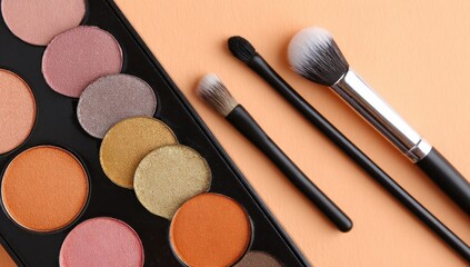 Makeup palette with various shades and matching makeup brushes arranged on a peach background.
