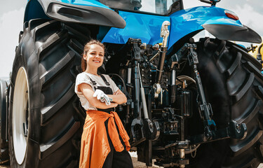 Woman at work. Portrait of female farm worker posing near agricultural tractor. © Barillo_Images