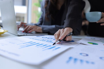 Hand of business team holding a pen, discussing marketing analytics at the office.