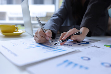 Hand of business team holding a pen, discussing marketing analytics at the office.