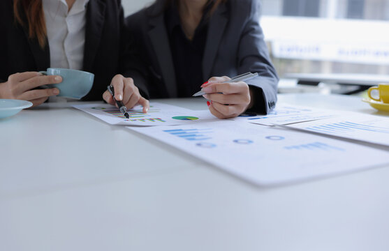 Hand of business team holding a pen, discussing marketing analytics at the office.