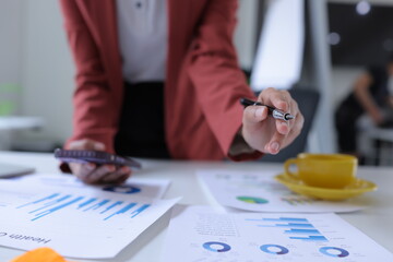 Hand of businesswoman holding a pen, discussing marketing analytics at the office.