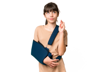 Little caucasian girl with broken arm and wearing a sling over isolated background with fingers crossing and wishing the best