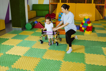 Physiotherapist assists a young boy with musculoskeletal disorders using mobility aids during rehabilitation exercises