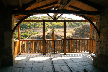 Exterior view of a historic Eastern Orthodox monastery built from stone with traditional Byzantine-style architecture, terracotta roof tiles, wooden stairways and large ceramic pots with plants