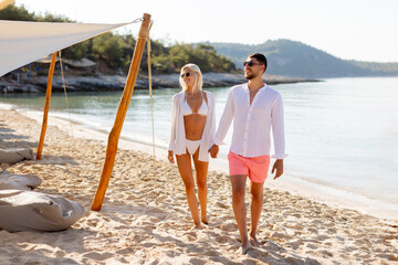 Couple enjoys a romantic beach stroll during a sunny afternoon by the shore
