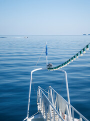 View from the bow of a boat decorated with string lights over the calm blue waters of the Aegean Sea in Greece.  Perfect image to capture the essence of sailing, slow travel, 