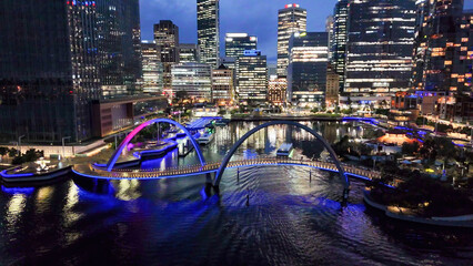 Night panorama of Elizabeth Quay and curved pedestrian bridge in Perth seen from aerial drone