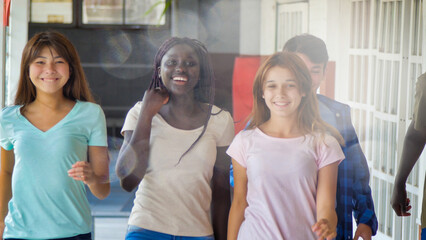 Happy multi ethnic group  of teenagers at school walking in the hallway. Happiness and lightheartedness concept