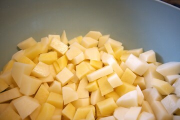 Freshness raw potatoes cut into cubes in a bowl, prepared for cooking or baking.