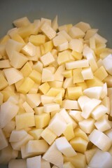 Freshness raw potatoes cut into cubes in a bowl, prepared for cooking or baking.