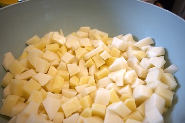 Freshness raw potatoes cut into cubes in a bowl, prepared for cooking or baking.