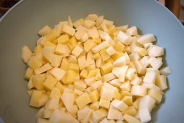 Freshness raw potatoes cut into cubes in a bowl, prepared for cooking or baking.