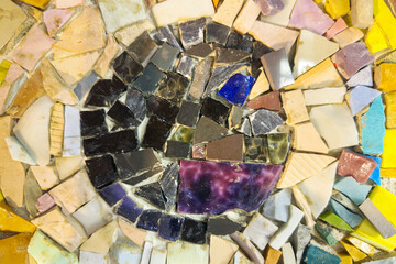 Jagged broken stone pieces in various shades forms a textured base. Shimmering, iridescent fragments are meticulously arranged in a circular pattern. Natural decorative mosaic elements background.
