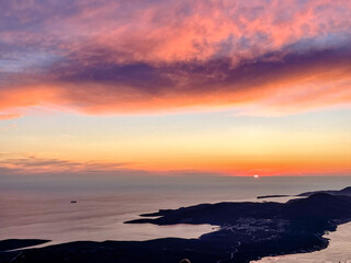 An exquisite sunset illuminates the horizon over a tranquil coastline, a breathtaking natural scene.
